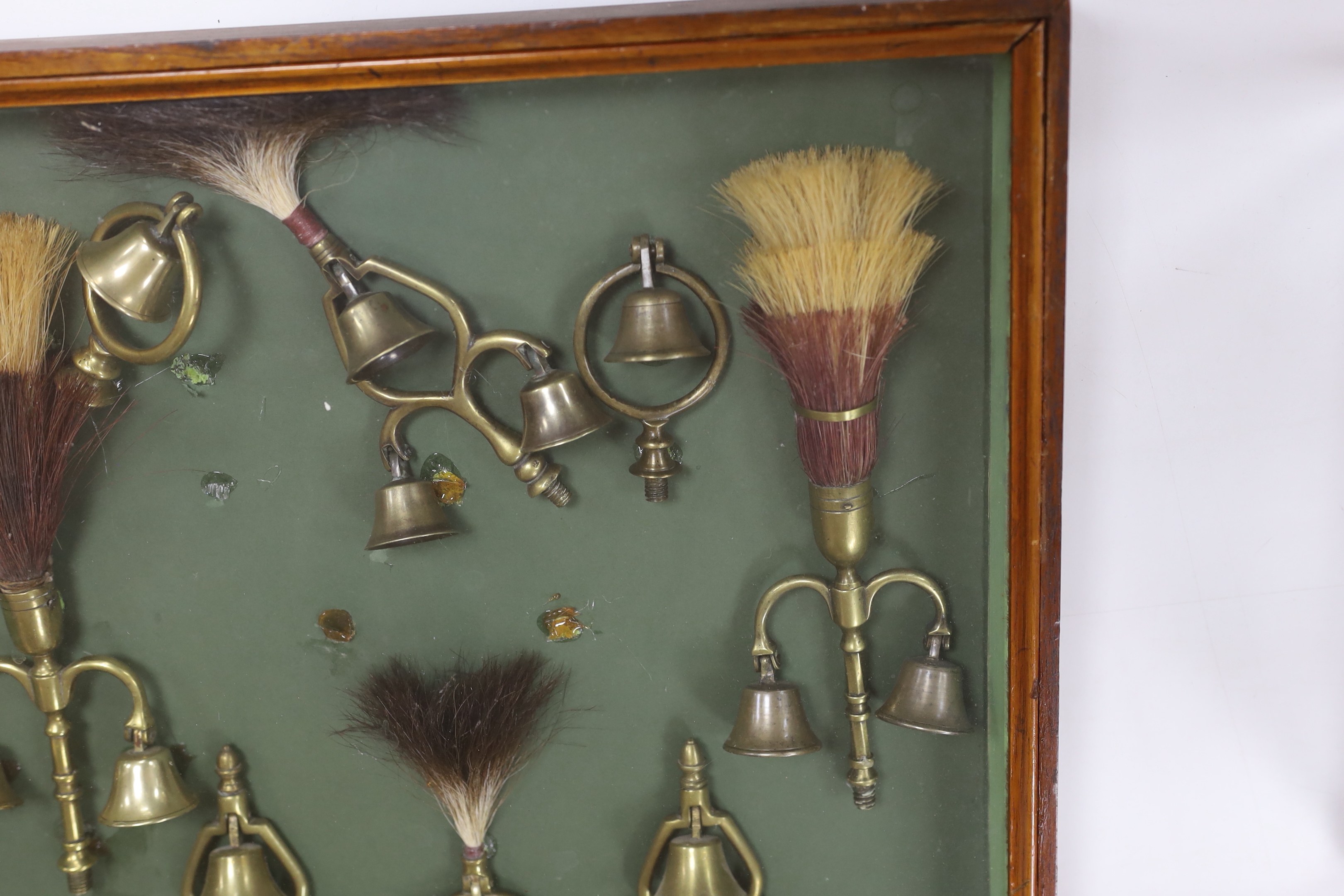 A collection of Victorian horse brass bell terrets, housed in a display case, 46cm high